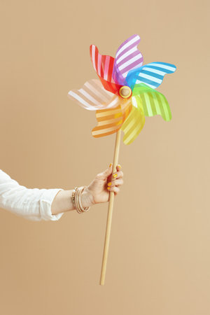 Beach vacation. Closeup on woman isolated on beige background with windmill toy.の写真素材