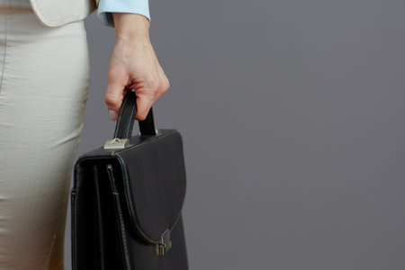 Closeup on woman worker with briefcase against gray background.