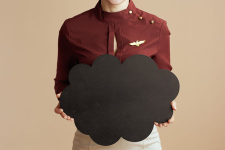 Closeup on stewardess woman isolated on beige background with cloud shaped blackboard.