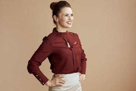 happy modern stewardess woman against beige background looking at copy space.の写真素材
