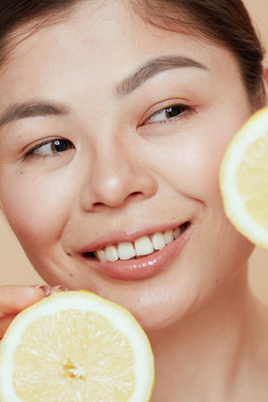 young woman with lemon on beige background.の写真素材