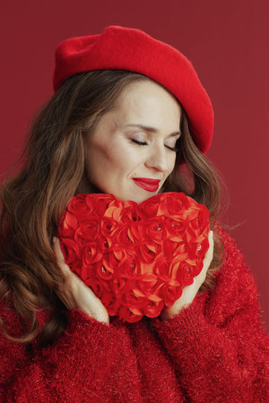 Happy Valentine. relaxed trendy middle aged woman in red sweater and beret with red heart.の写真素材