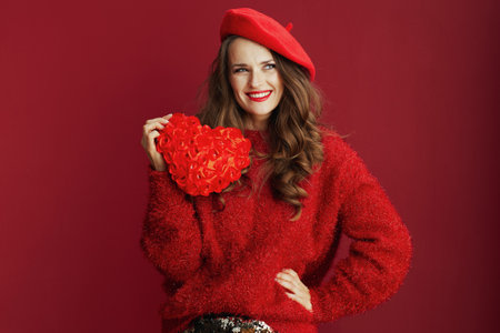 Happy Valentine. smiling stylish woman in red sweater and beret with red heart and long wavy hair.の写真素材