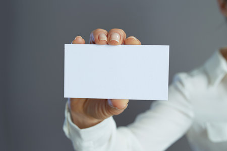 Closeup on small business owner woman with business card isolated on gray.の写真素材
