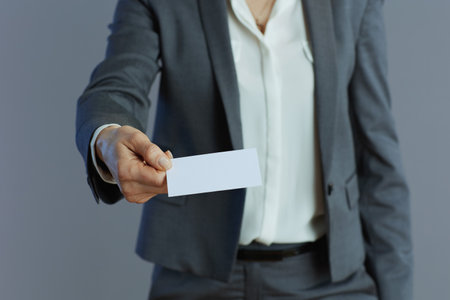 Closeup on business woman in gray suit with business card isolated on gray background.の写真素材