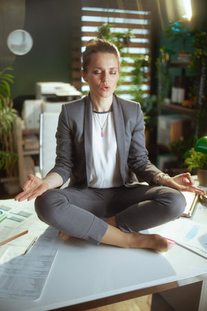 Sustainable workplace. relaxed modern business woman in modern green office meditating.の写真素材