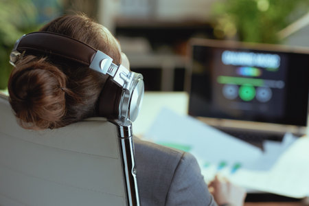 Closeup on modern business woman with laptop listening to the music with headphones in modern office.の写真素材
