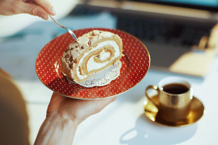 Closeup on modern female with piece of cake and cup of coffee in modern office.