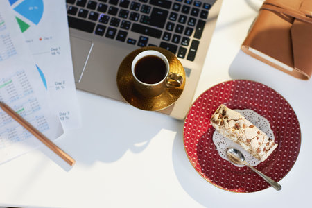 Mental health at work concept. Upper view of table in modern office with piece of cake, cup of...