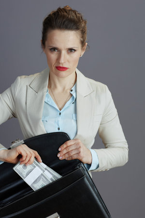 stylish middle aged woman worker in a light business suit with briefcase and dollars money packs...