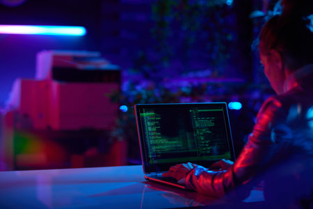 Seen from behind modern business woman with laptop programming in modern office.の写真素材