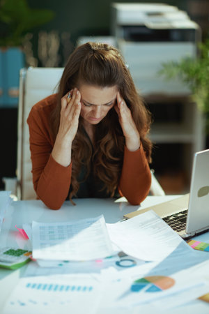stressed 40 year old small business owner woman working with documents in the modern green office.の写真素材