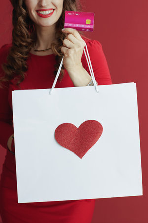 Happy Valentine. Closeup on female with credit card and shopping bag and heart.の写真素材