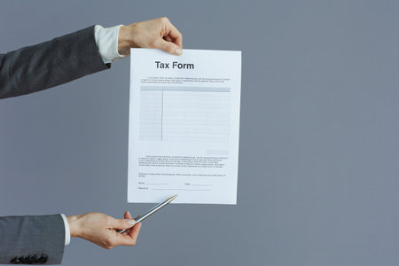 Closeup on female worker in gray suit with tax form isolated on gray.の写真素材