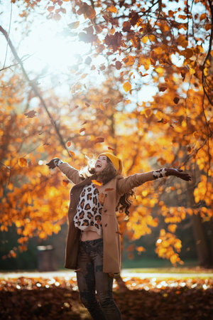 Hello September. happy elegant middle aged woman in beige coat and orange hat rejoicing outdoors on...