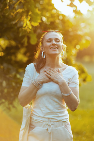 Summer time. smiling trendy female in white shirt with hand on chest outdoors.の写真素材