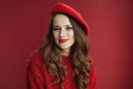 Happy Valentine. happy modern woman with long wavy hair in red sweater and beret against red background.の写真素材