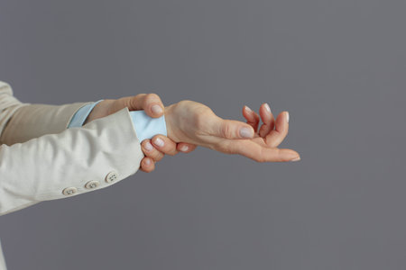 Closeup on small business owner woman in a light business suit with carpal tunnel syndrome against...