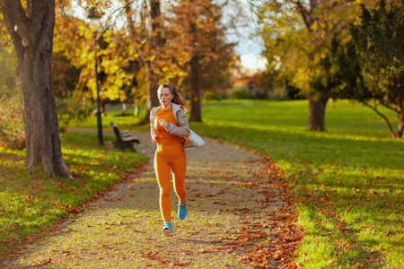 Hello autumn. young woman in fitness clothes running in the park.の写真素材