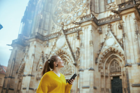 happy trendy traveler woman in yellow blouse in Prague Czech Republic with smartphone sightseeing and walking.の写真素材
