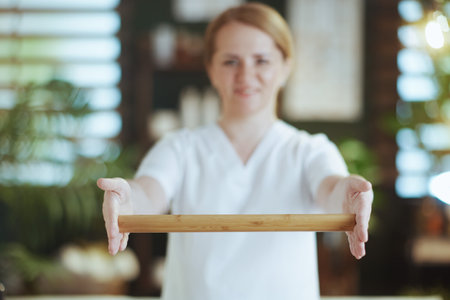Healthcare time. Closeup on female massage therapist in spa salon with wooden massage stick.の写真素材