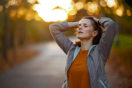 Hello autumn. relaxed fit woman in fitness clothes in the park relaxing after workout.の写真素材