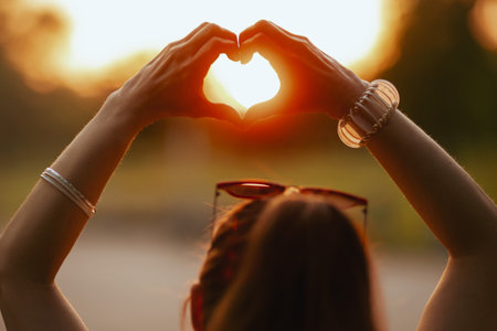 Summer time. happy elegant middle aged woman in white shirt showing heart shaped hands.の写真素材