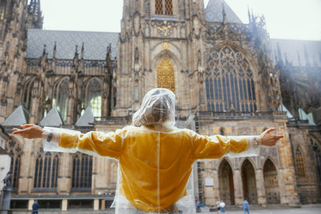 Seen from behind woman in yellow blouse and raincoat in Prague Czech Republic enjoying promenade and rejoicing.の写真素材