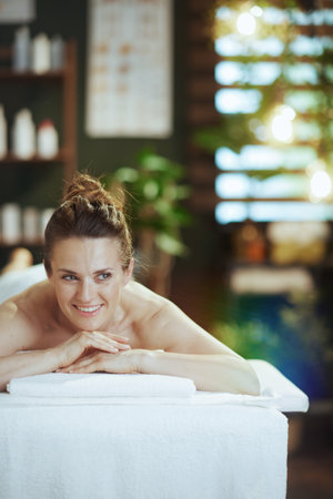 Healthcare time. happy modern 40 years old woman in massage cabinet laying on massage table.の写真素材