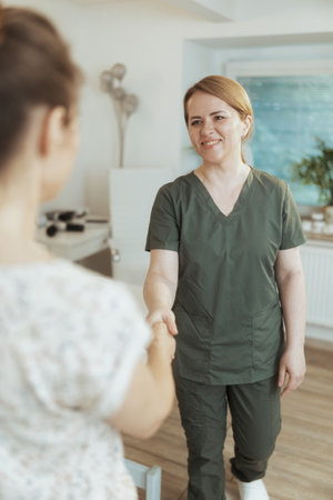 Healthcare time. smiling female massage therapist in massage cabinet with client shaking hands.の写真素材
