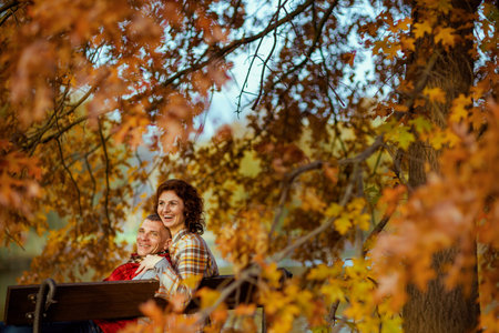 Hello autumn. happy stylish couple in the park sitting on a bench.