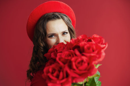 Happy Valentine. elegant 40 years old woman in red dress and beret on red background with red roses.の写真素材