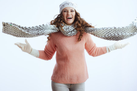 Hello winter. happy trendy woman in sweater, mittens, hat and scarf against white background.の写真素材