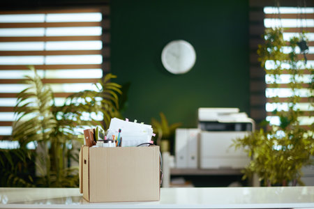 New job. table in modern green office with personal belongings in cardboard box.の写真素材