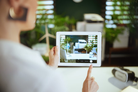 Eco real estate business. Closeup on business woman in green office in white blouse with tablet PC...