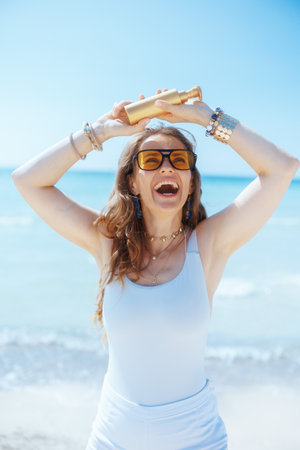 smiling elegant 40 years old woman on the ocean coast with spf.の写真素材