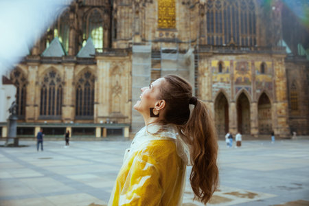 happy modern tourist woman in yellow blouse and raincoat in Prague Czech Republic enjoying promenade.の写真素材