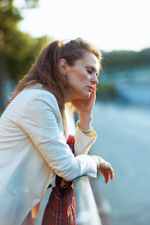 trendy female in pink dress and white jacket in the city with red bag.の写真素材