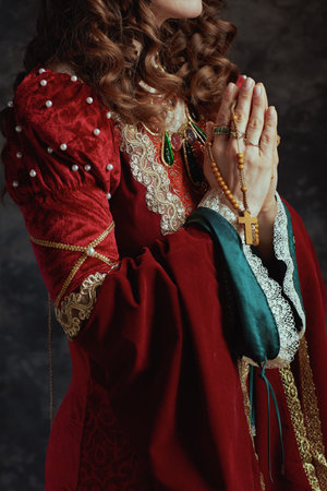 Closeup on medieval queen in red dress with rosary praying.の写真素材