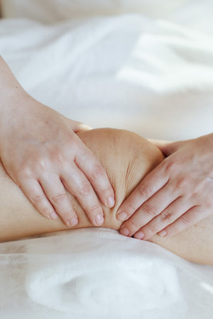 Healthcare time. Closeup on medical massage therapist in massage cabinet massaging clients leg.