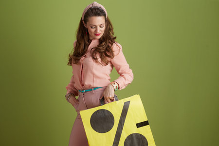 pensive modern female against green background in pink blouse with sale shopping bag.