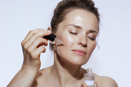 relaxed 40 years old woman with cosmetic elixir against white background.