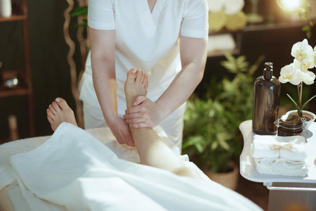 Healthcare time. Closeup on medical massage therapist in massage cabinet massaging clients foot on massage table.の写真素材