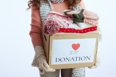 Hello winter. Closeup on modern woman in sweater, mittens, hat and scarf isolated on white background with donation box.の写真素材