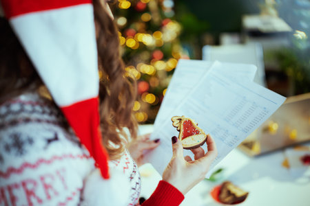 Christmas time. Closeup on with documents and cookie in santa hat in green office with Christmas tree.の写真素材