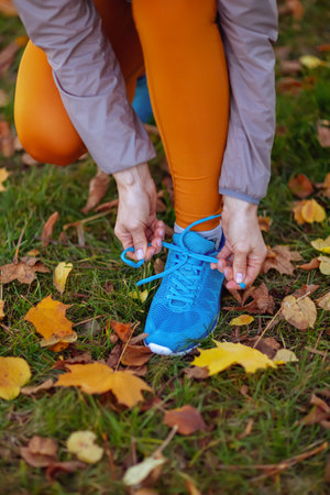 Closeup on woman in fitness clothes in the park tying shoelaces.の写真素材