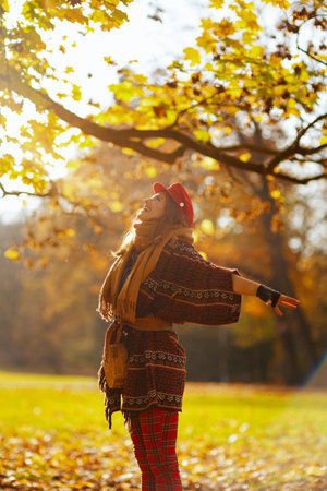 smiling middle aged woman in red hat with scarf and gloves rejoicing in the city park.の写真素材