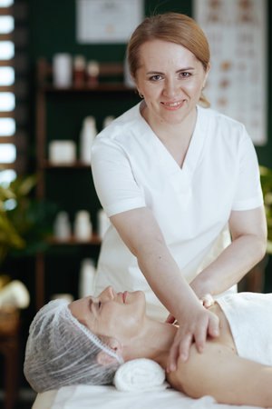 Healthcare time. massage therapist in spa salon massaging clients shoulder on massage table.の写真素材
