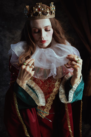 medieval queen in red dress with white collar and crown on dark gray background.の写真素材