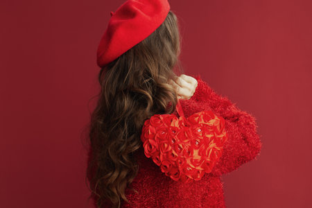 Happy Valentine. Seen from behind woman in red sweater and beret with red heart.の写真素材